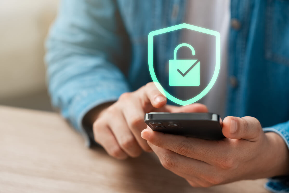 Person's hands holding a smart phone to complete a mobile payment. A graphic of a lock hovers above to show the secure process.