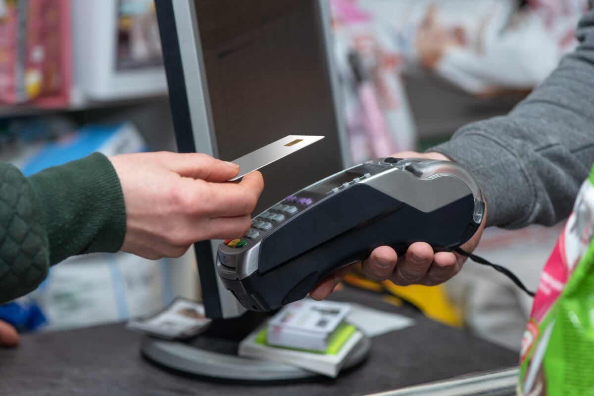 Customer holding a credit card over a mobile credit card terminal to complete a contactless payment